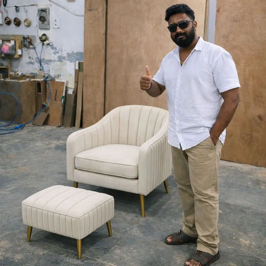 “Vicky Anand, founder of Shanthi Sofa Works, standing beside a custom luxury lounge chair and ottoman in the Bangalore furniture workshop.”